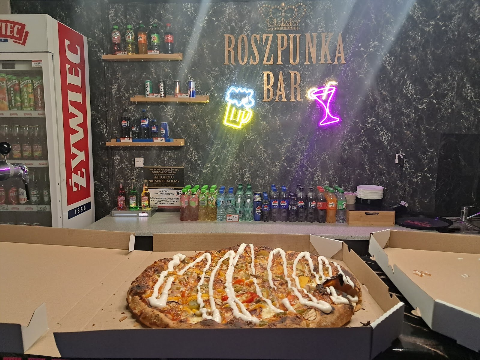 Pizza w Roszpunce na tle baru i kolorowych neonów